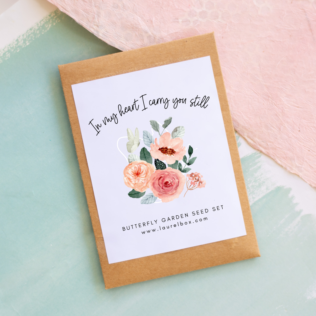 photo of a brown seed packet with the words "In my heart I carry you still" above pink flowers with the words "butterfly garden seed set" under the flowers