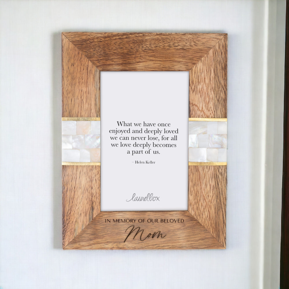 photo of a wooden photo frame with a white mosaic pattern on either side of the frame and a white piece of paper displaying "What we have once enjoyed and deeply loved we can never lose, for all we love deeply becomes a part of us - Helen Keller" with the words In Memory Of Our Beloved Mom engraved at the bottom