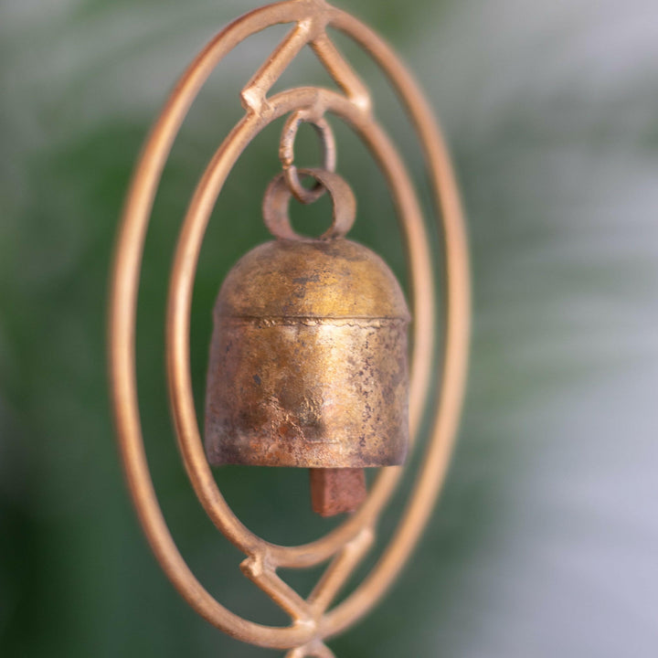 Close-up of a rustic wind chime of recycled tin and iron coated in copper showcasing one bell