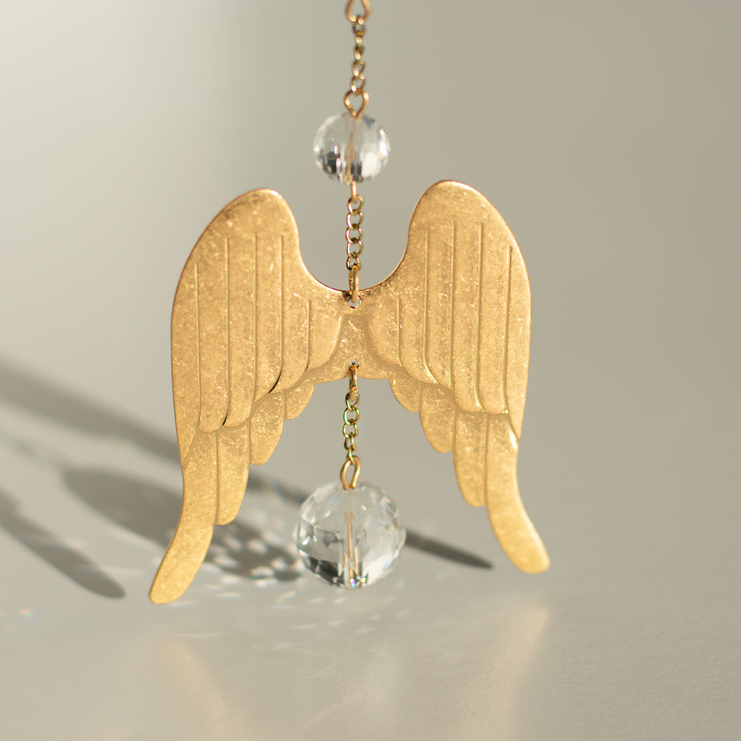 gold chain with gold angel wings with clear crystals above and below the angel wings
