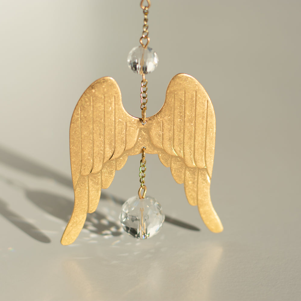 gold chain with gold angel wings with clear crystals above and below the angel wings