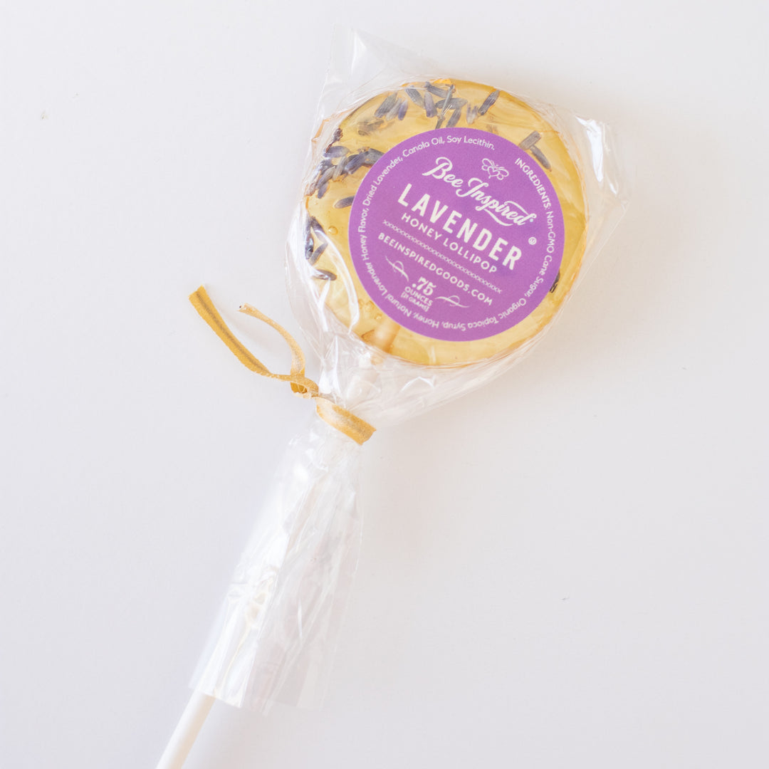 photo of a yellow lollipop with a purple circular sticker with the words " Bee Inspired Lavender Honey Lollipop"