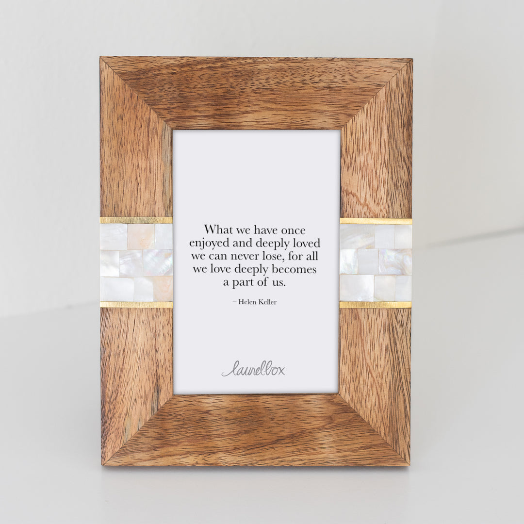 photo of a wooden photo frame with a white mosaic pattern on either side of the frame and a white piece of paper displaying "What we have once enjoyed and deeply loved we can never lose, for all we love deeply becomes a part of us - Helen Keller"
