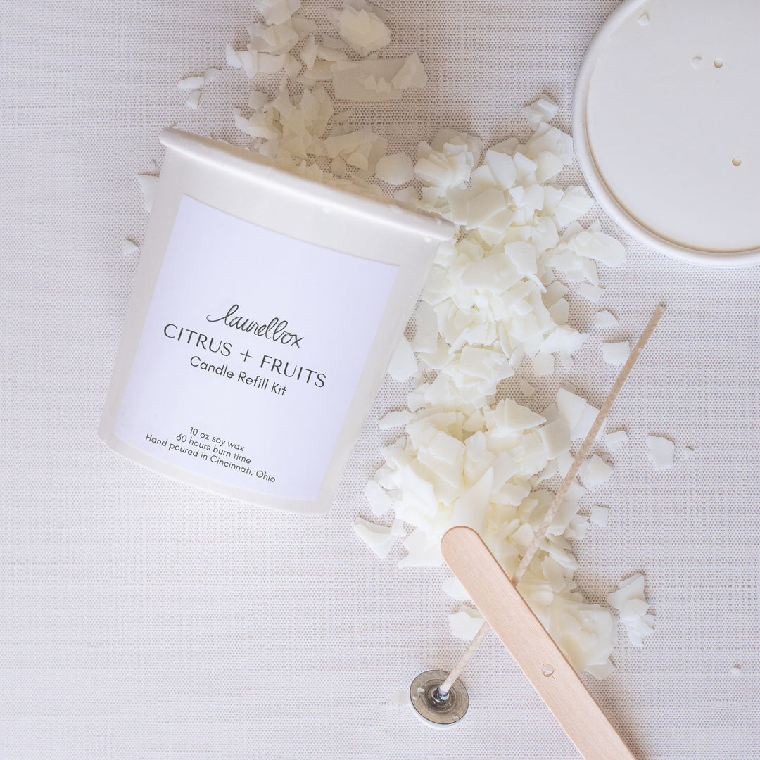 A Citrus and Fruits Candle Refill Kit container with scattered wax across the white background