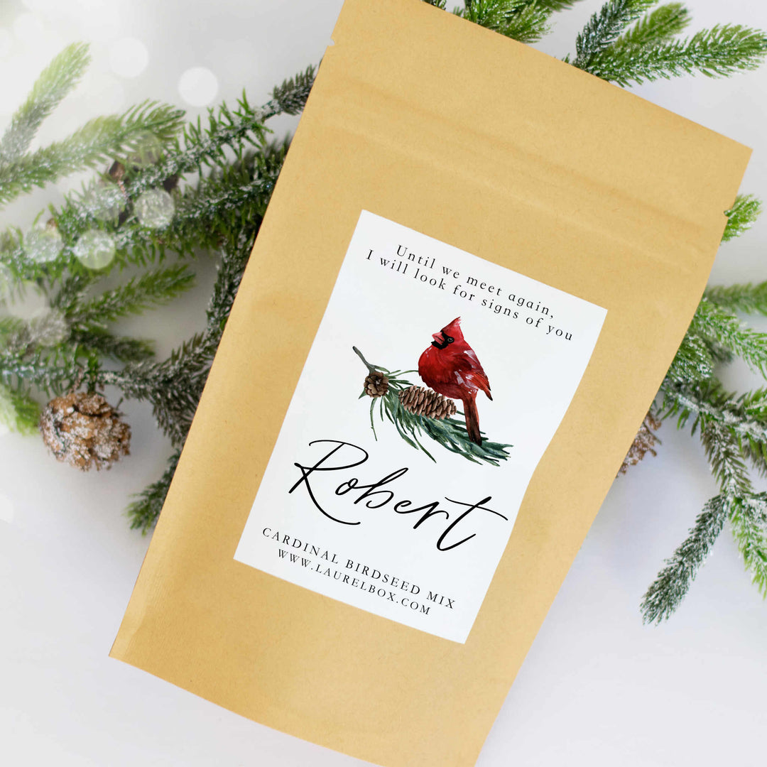 A close-up of a yellow bag with a white sticker that has a cardinal sitting on pine needles and pinecones with the text Robert below it.