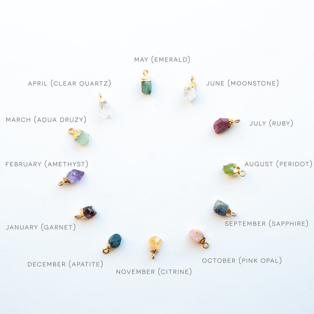 chart of all the birthstones by month in a circle: starting at the top with May ( emerald ), June ( Moonstone ), July ( Ruby ), August ( Peridot ), September ( Sapphire ), October ( Pink Opal ), November ( Citrine ), December ( Apatite ), January ( Garnet ), February ( Amethyst ), March ( Aqua Druzy ), April ( Clear Quartz )