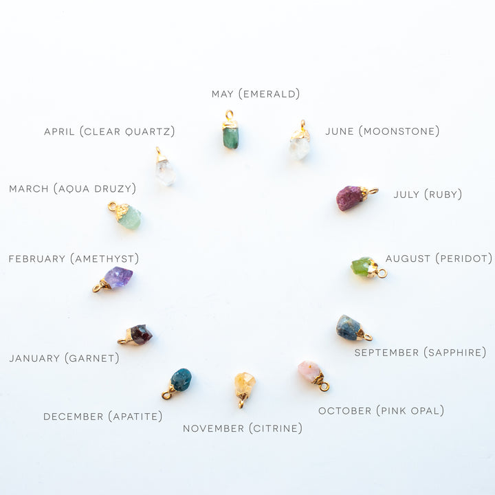 chart of all the birthstones by month in a circle: starting at the top with May ( emerald ), June ( Moonstone ), July ( Ruby ), August ( Peridot ), September ( Sapphire ), October ( Pink Opal ), November ( Citrine ), December ( Apatite ), January ( Garnet ), February ( Amethyst ), March ( Aqua Druzy ), April ( Clear Quartz )