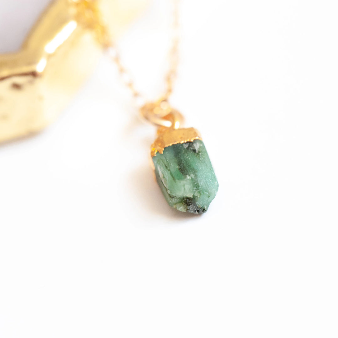 photo of a gold chain necklace with a green raw cut stone at the end