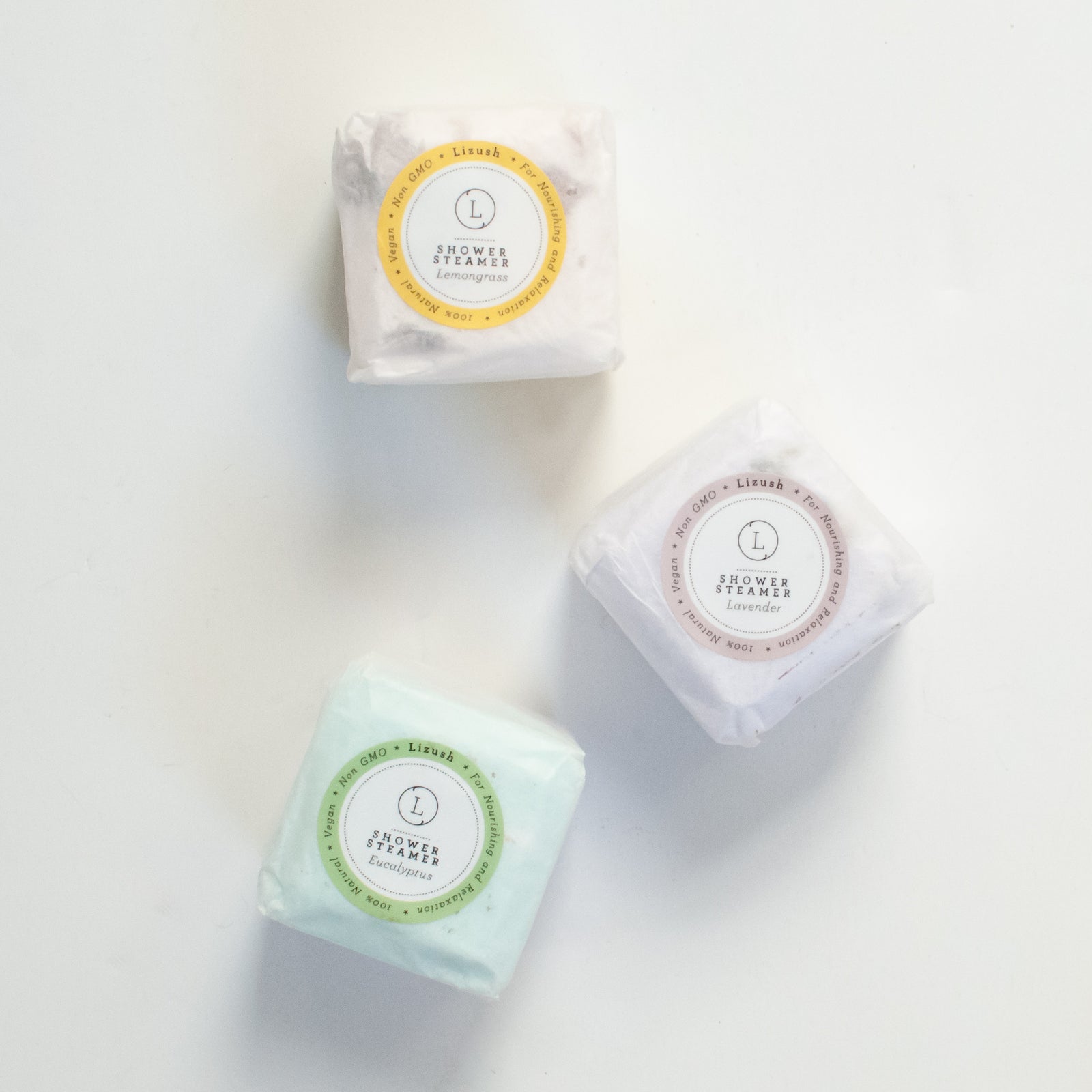 photo of three individually wrapped squares in yellow, purple and green each labeled "shower steamer"