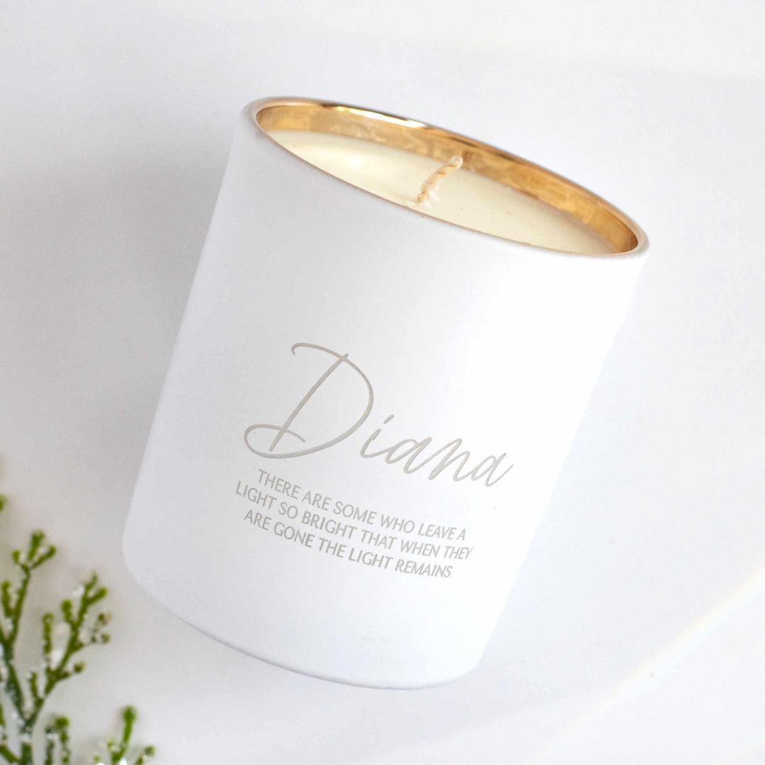 A white-coated candle with engraved text Diana There are some who leave a light so bright that when they are gone the light remains angled to the right against a white background