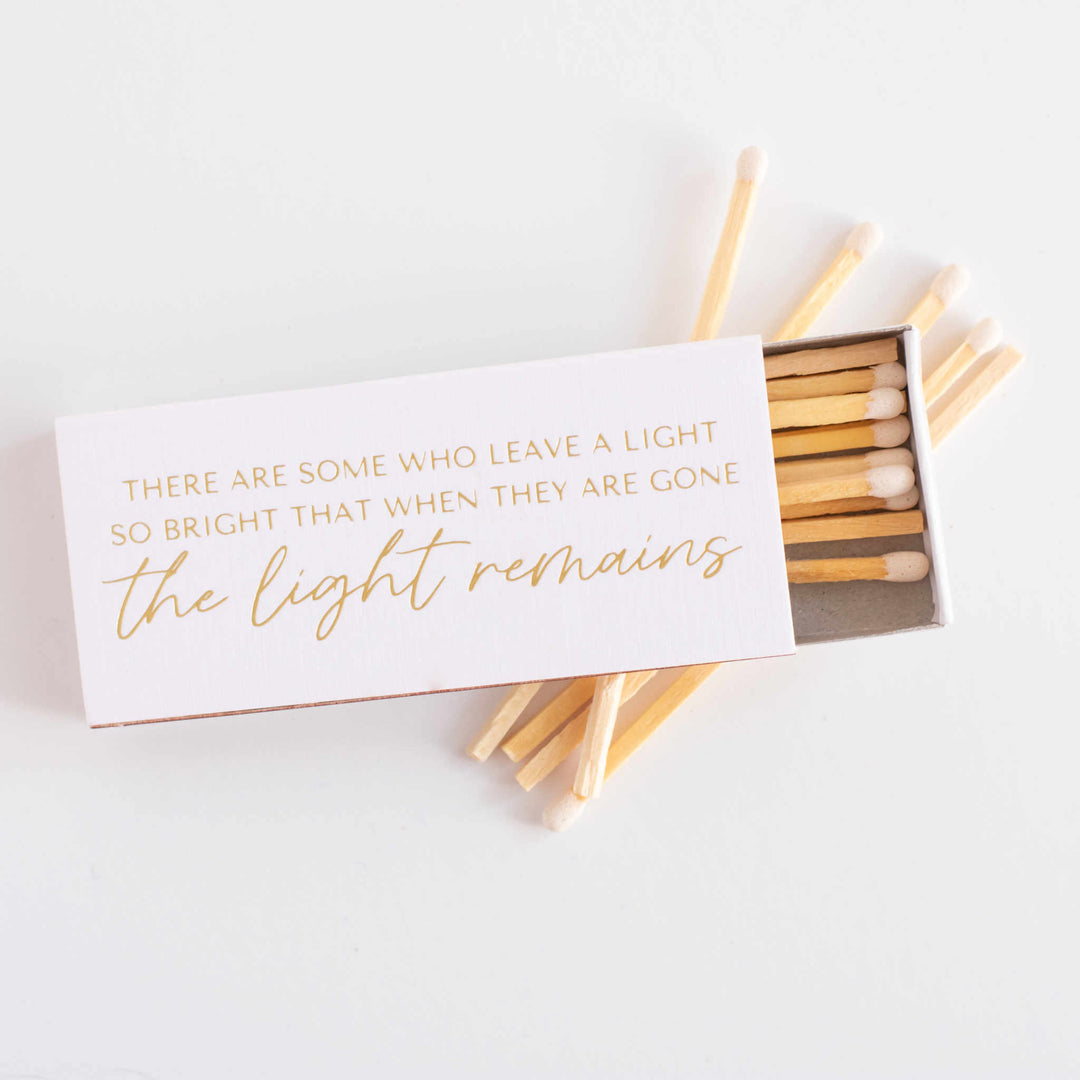 A tilted open box of matches with gold text on it. Scattered matches in the background