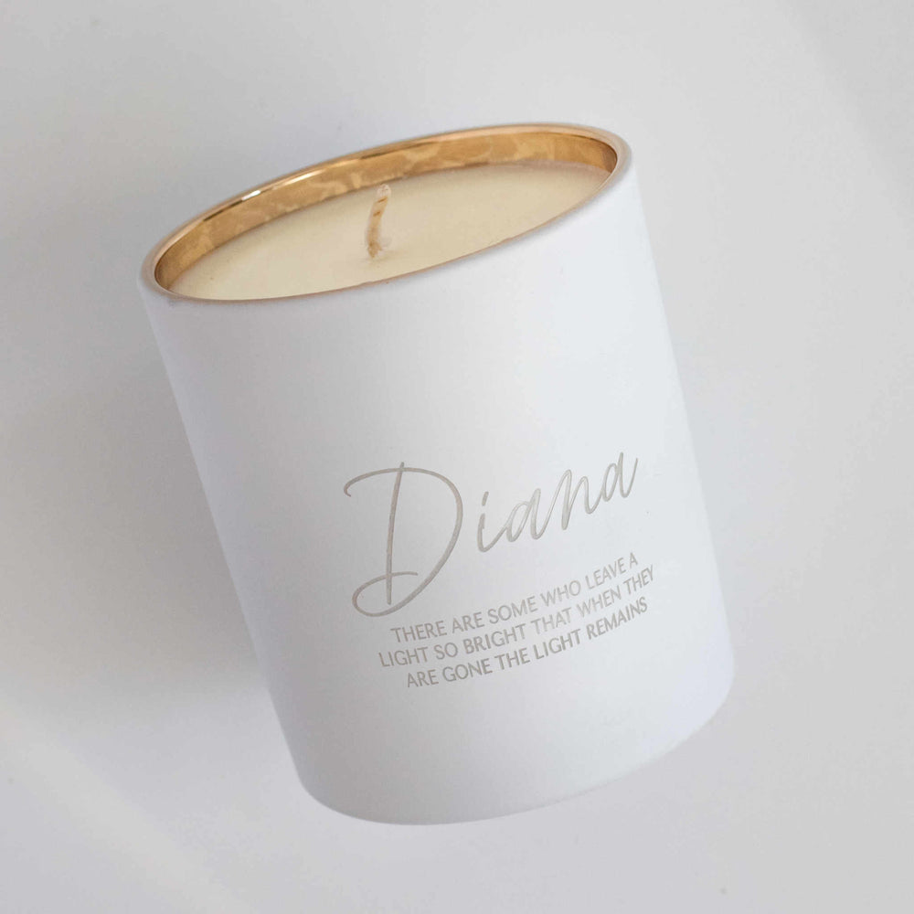 A white-coated candle with engraved text Diana There are some who leave a light so bright that when they are gone the light remains angled to the left against a white background.