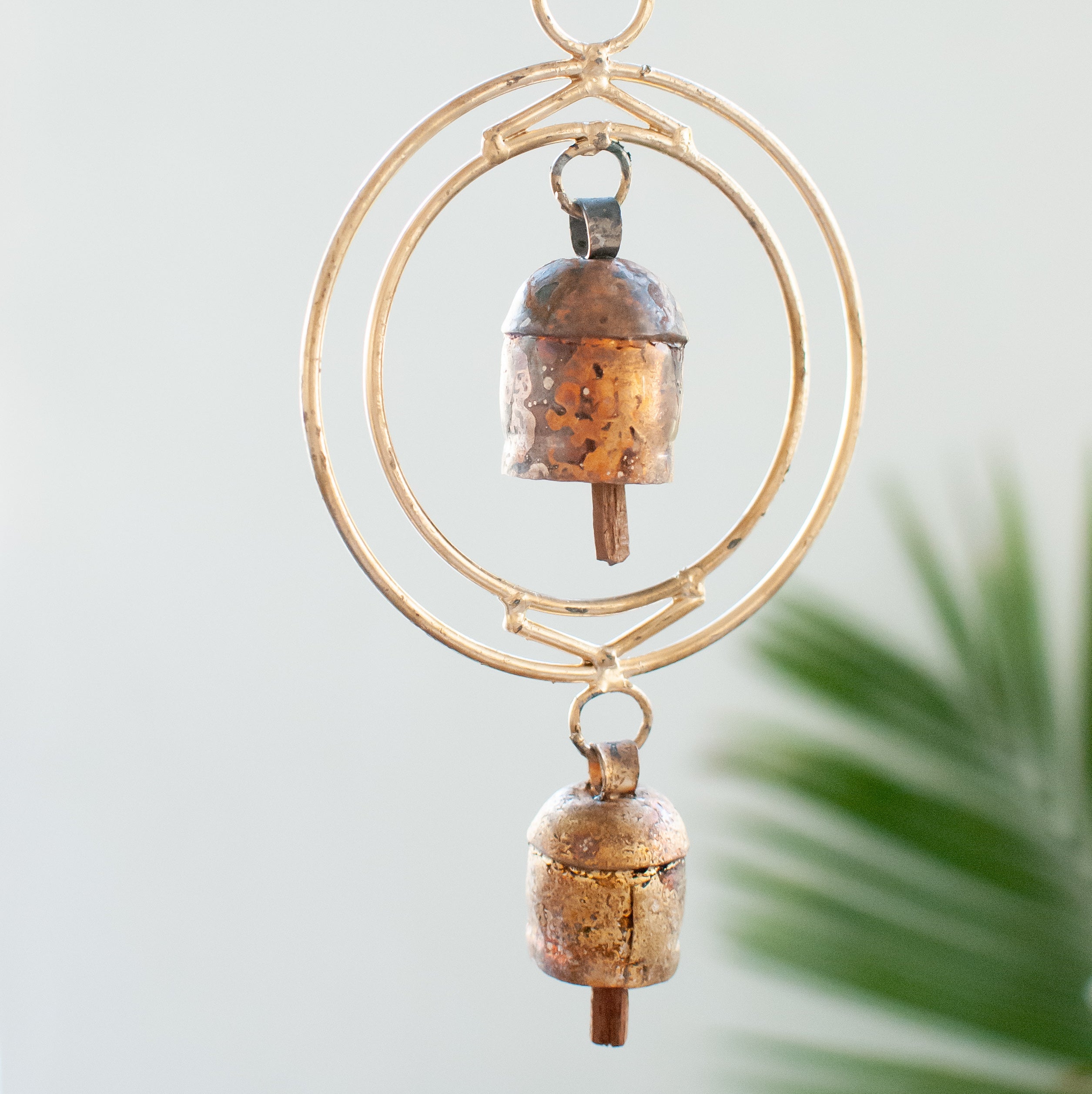 Close-up of a rustic wind chime of recycled tin and iron coated in copper with two bells.