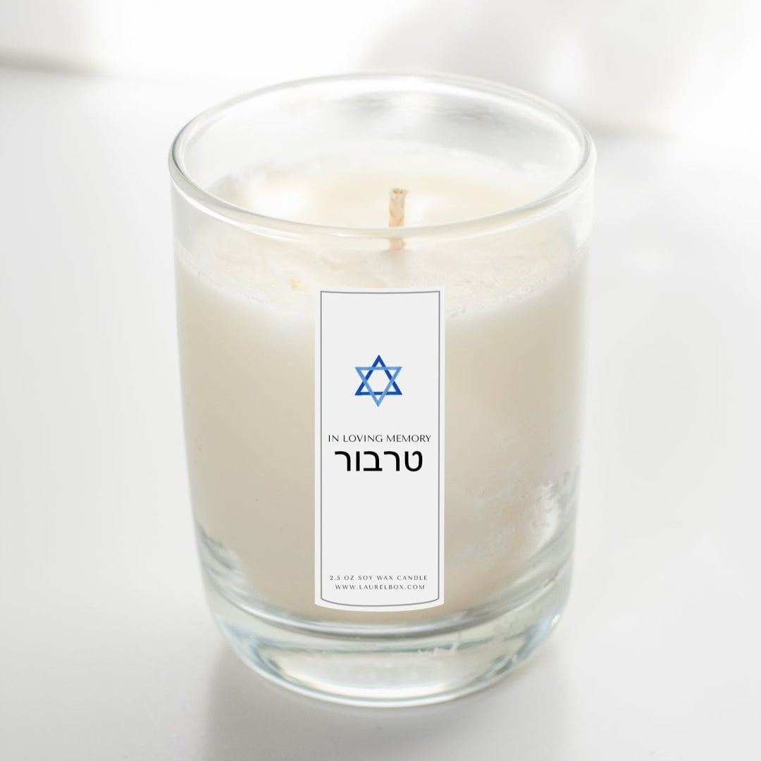 A glass candle with a white sticker sitting on a white surface