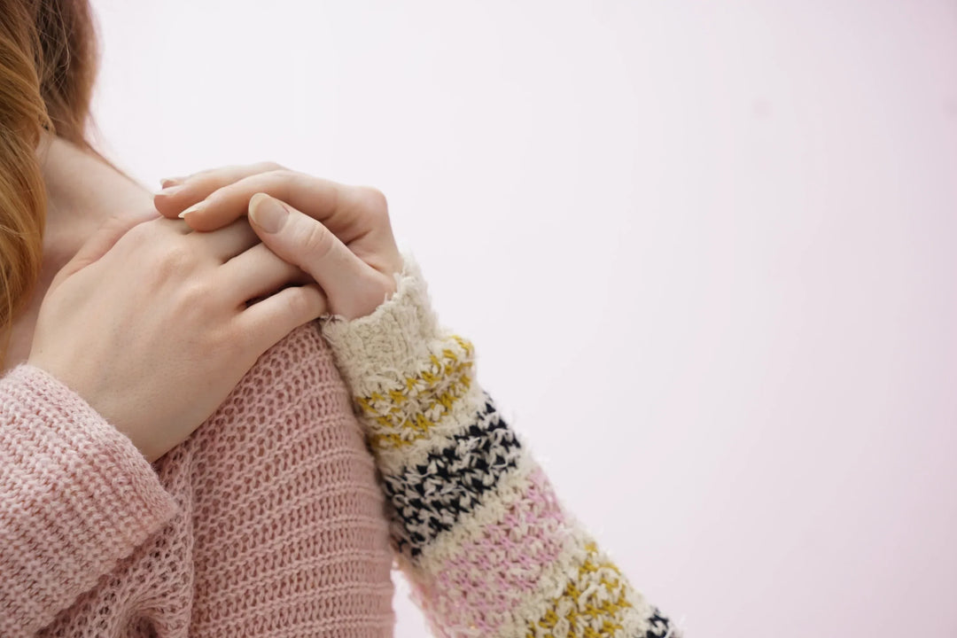 Ways to Support Someone Going Through a Pregnancy Loss, two hands showing comfort, one in a pink sweater and the other in a striped knit.