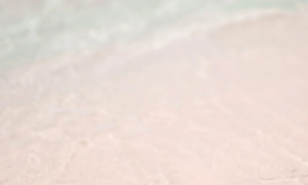 Soft waves on a sandy beach, pale pink sand with gentle water movement, reflecting calmness and tranquility, related to Grief Comes in Waves.