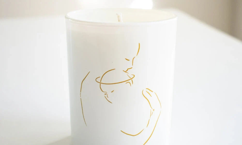 White candle with gold line art depicting a mother holding a child, designed as a remembrance gift.