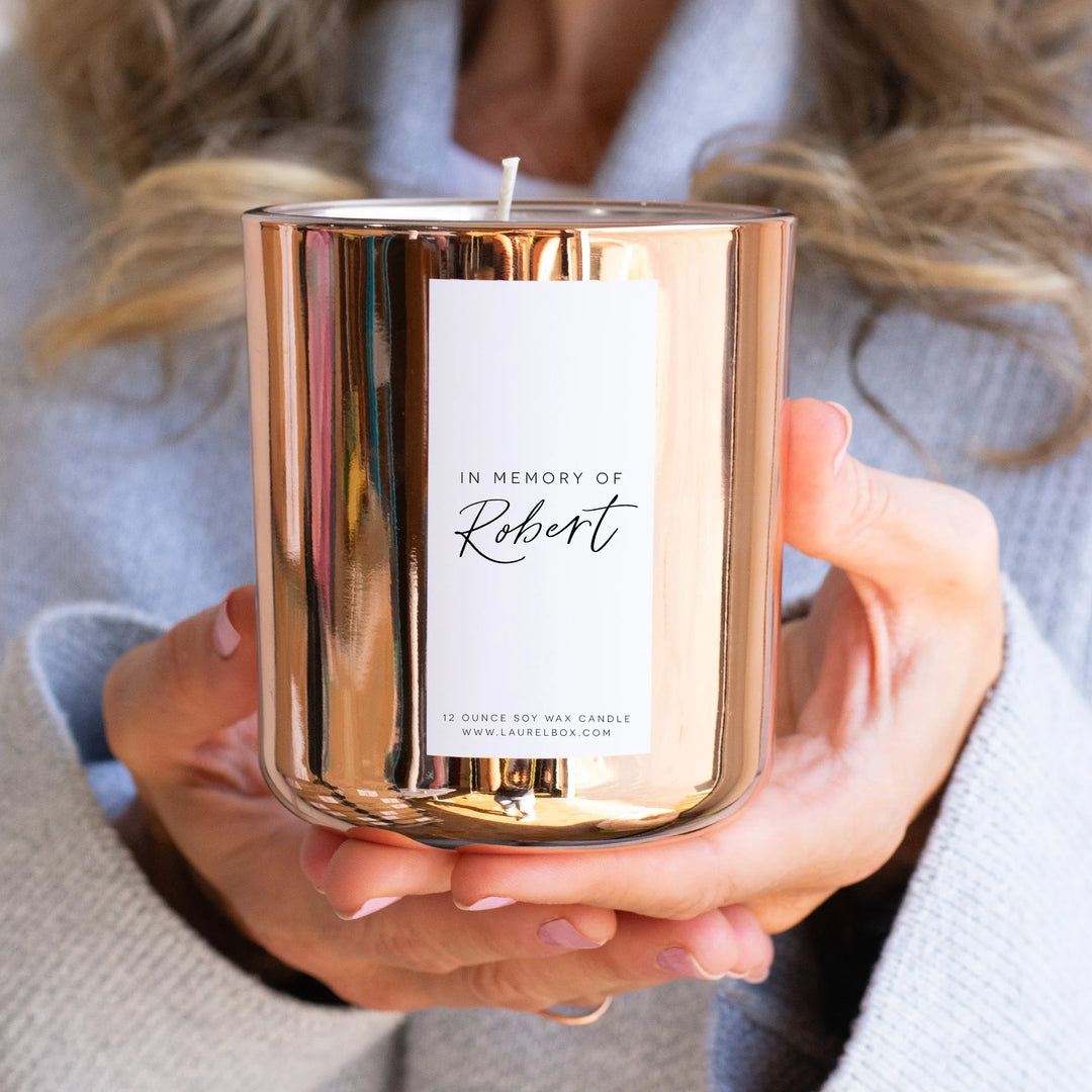 Memorial Candles That Keep Their Memory Alive: A Complete Guide. Rose gold candle with label "In Memory of Robert" and white text.