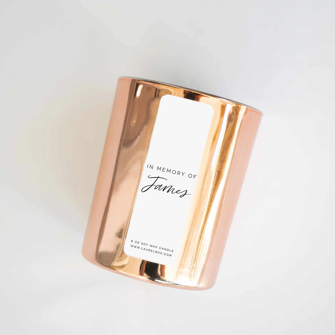 Copper candle holder with white label reading 'IN MEMORY OF James', soy wax, 8 oz, reflecting light, modern design. The Power of Candle Lighting: Honoring Lost Loved Ones with the Right Candle.