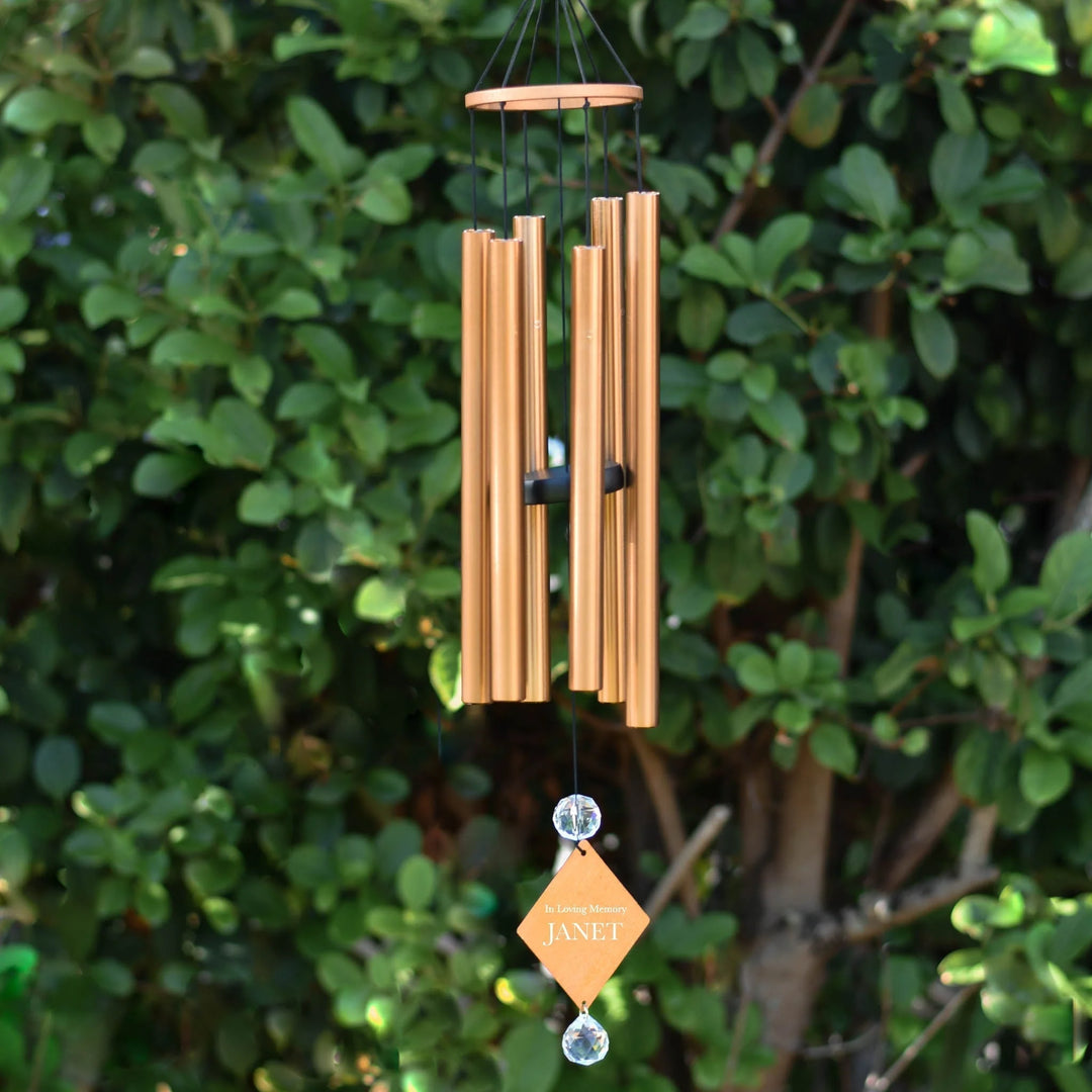 The Best Memorial Wind Chimes for Remembering a Loved One (2026 Edition). Golden chimes with a tag 'In Loving Memory JANET'