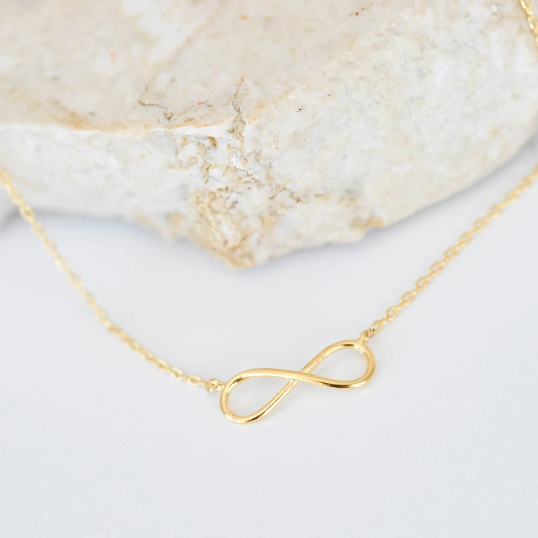 Gold infinity necklace on a smooth surface, designed as a remembrance gift. Top 12 Memorial Jewelry Picks for 2026 Guide.