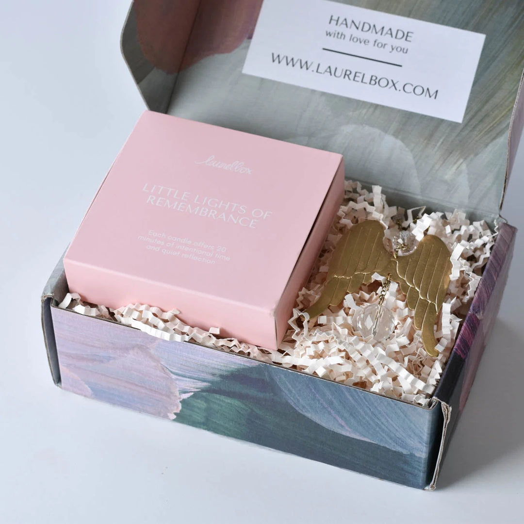 The Best Sympathy Gifts for 2026: Picks Under $25, $50, $100. A pink box labeled "Little Lights of Remembrance" next to angel wings charm.
