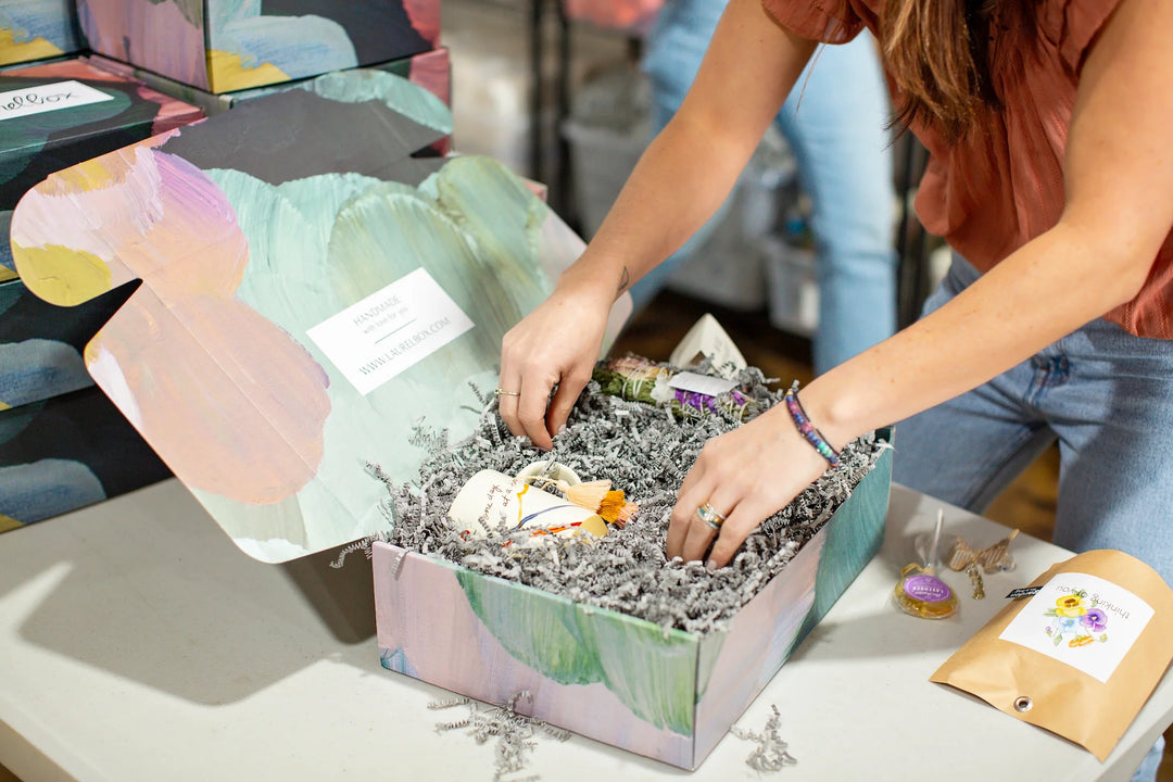 Colorful floral care package with shredded paper, including a condolence gift box and memorial keepsakes. What to Include in a Care Package for a Grieving Friend.