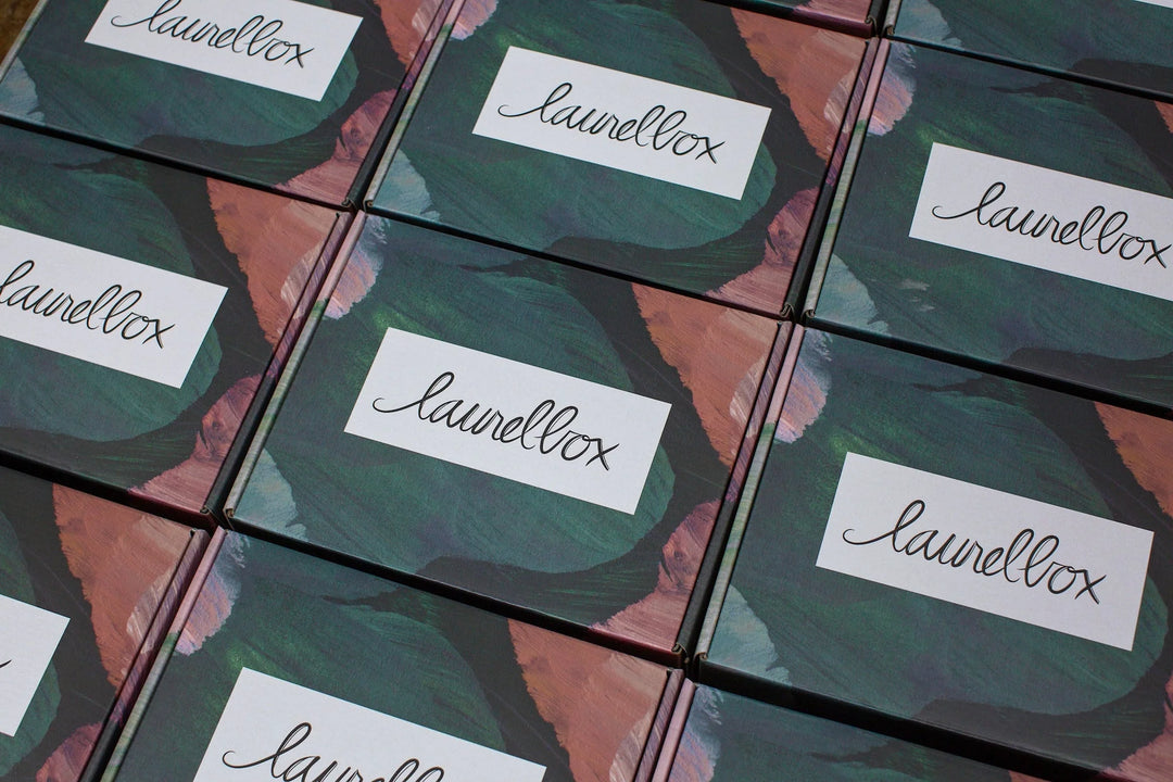 Colorful boxes with a green and pink design, labeled "laurellox" in elegant script, for condolence gift box.