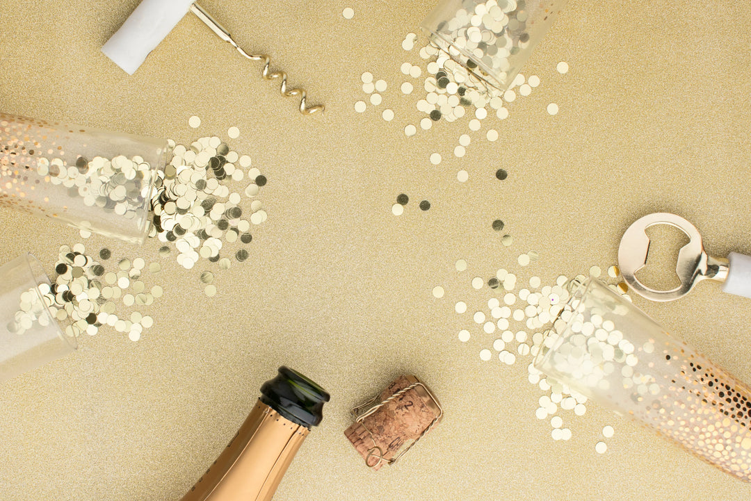 Grief in the New Year: Three Tips For Honoring Loss; scattered confetti around champagne glasses and a cork.