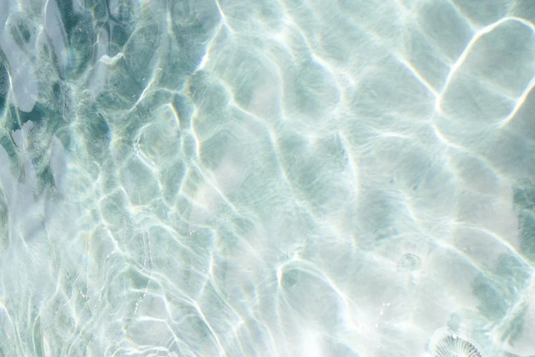 Clear water surface reflecting light, creating rippling patterns, illustrating summer themes for coping with grief in the summer.