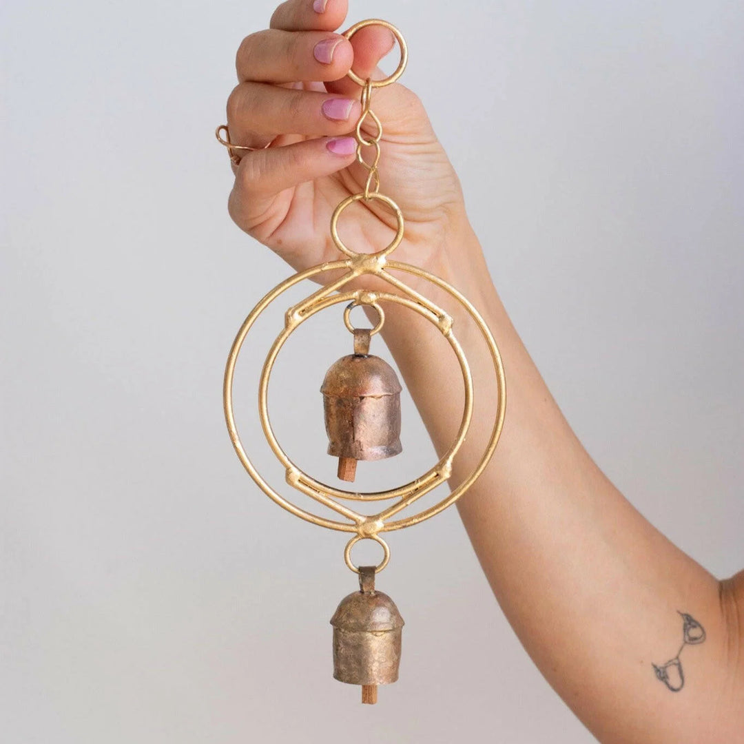 Custom Engraved Memorial Wind Chimes: Ideas and Where to Buy. Hand holding a gold circular wind chime with two metal bells.
