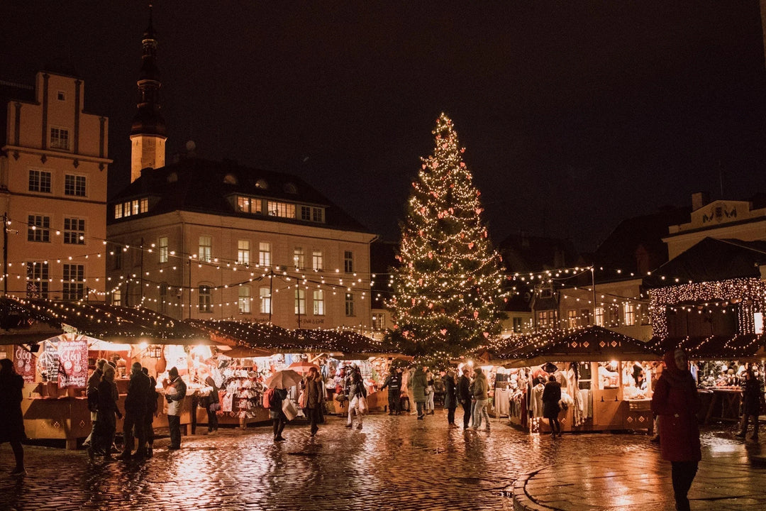 Market scene at night with a large decorated Christmas tree and illuminated stalls. How To Support Your Community & Those Grieving During The Holidays.