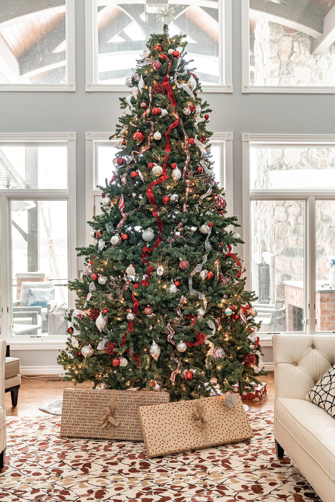 Christmas tree with red and silver ornaments, ribbon decorations, and wrapped gifts, in a cozy living room. Balancing Grief and Gratitude During the Holidays.