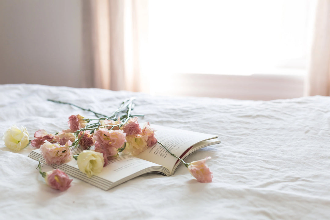 Thoughtful Sympathy Gifts for Non-Religious Friends & Family: open book with pink and white flowers on a white bedspread.