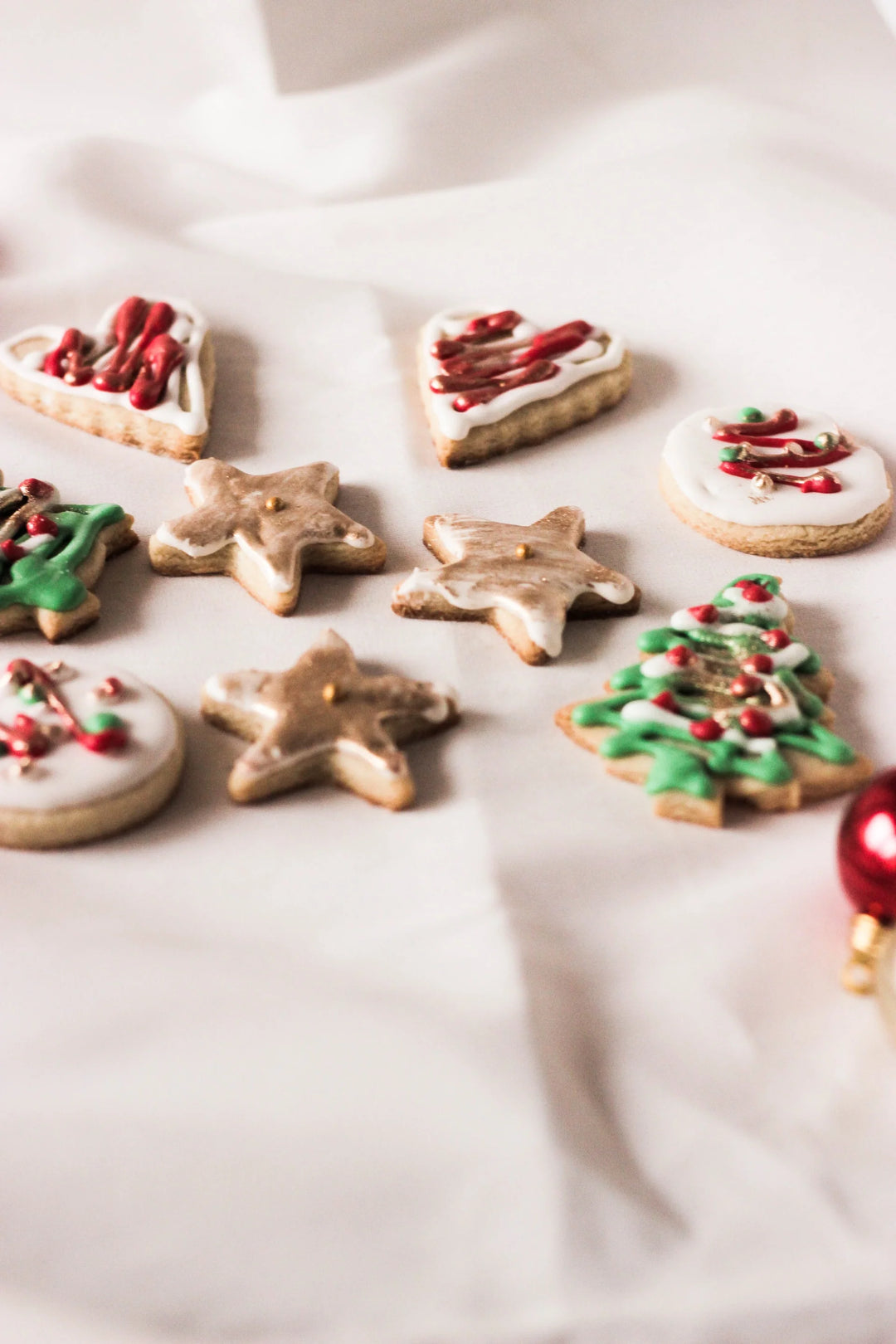 Holiday Remembrance Traditions to Start for Loved Ones, decorated holiday cookies on a white cloth, heart, star, tree shapes.