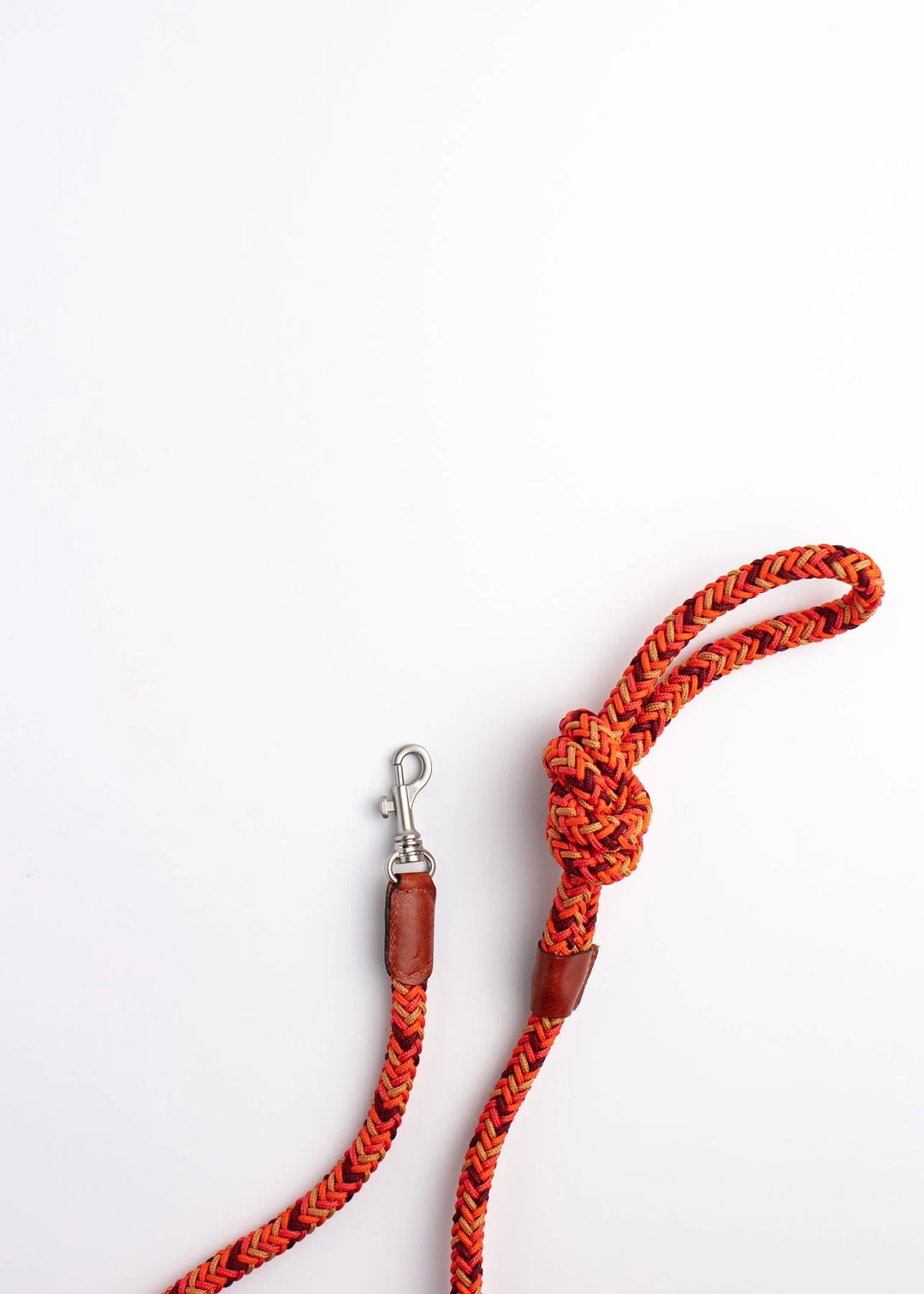 Braided rope dog leash in red and orange with leather handle and metal clip, featuring a knot at one end.