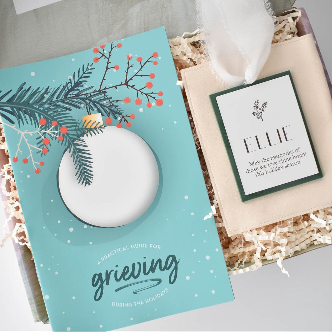 Memories Shine Bright Holiday Gift Box with a guide for grieving and a tag reading 'ELLIE', presented in shredded paper.