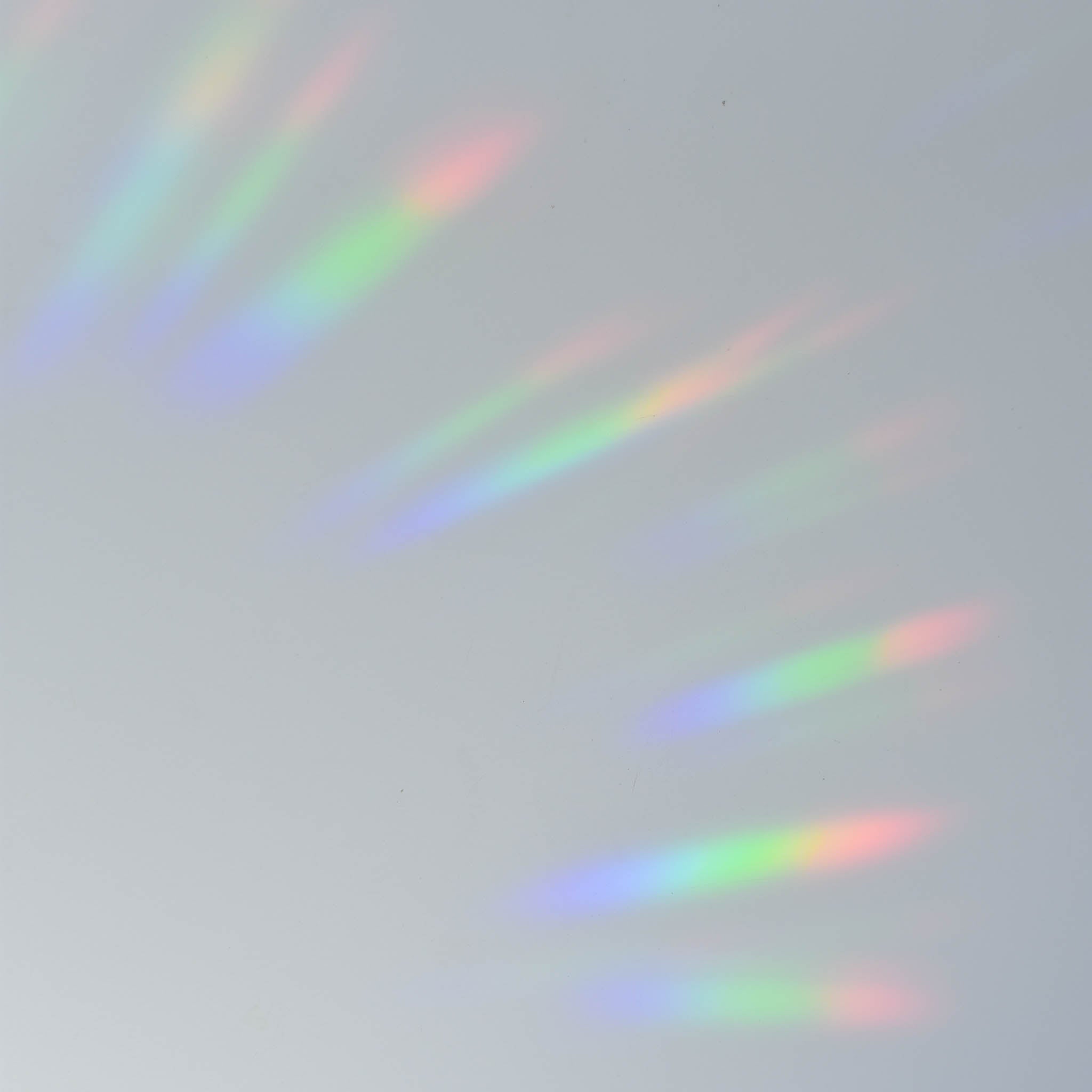 Colorful light streaks in rainbow hues projected on a soft gray surface.