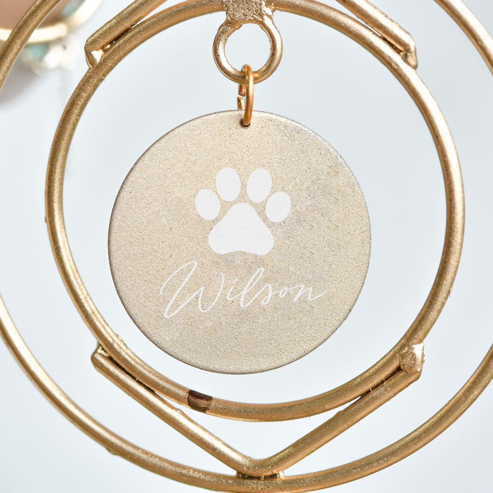 Dog Loss Wind Chime gold circular tag with paw print and engraved name 'Wilson', hanging from a gold metal frame.