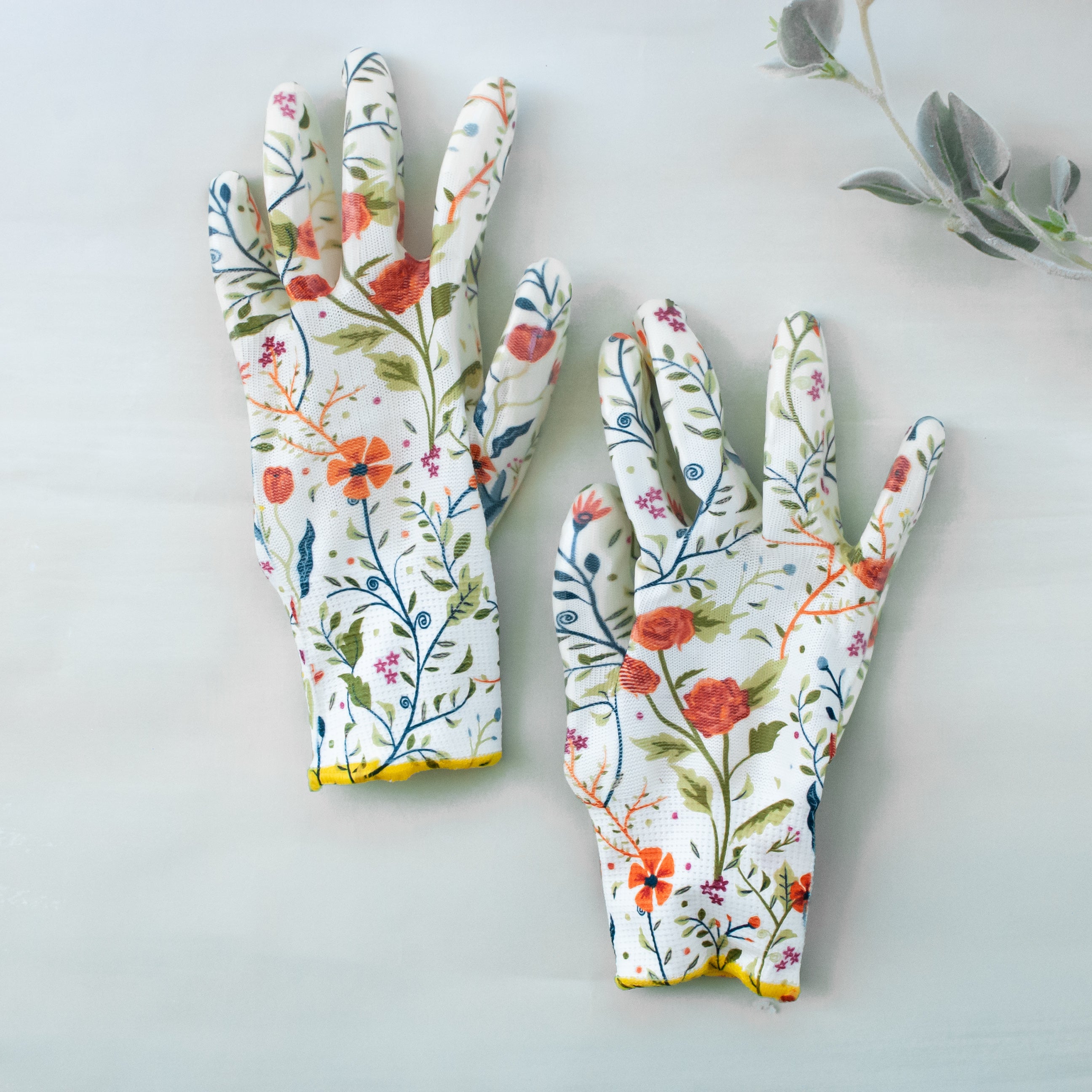 photo of two white gardening gloves with multi colored flowers displayed on the gloves