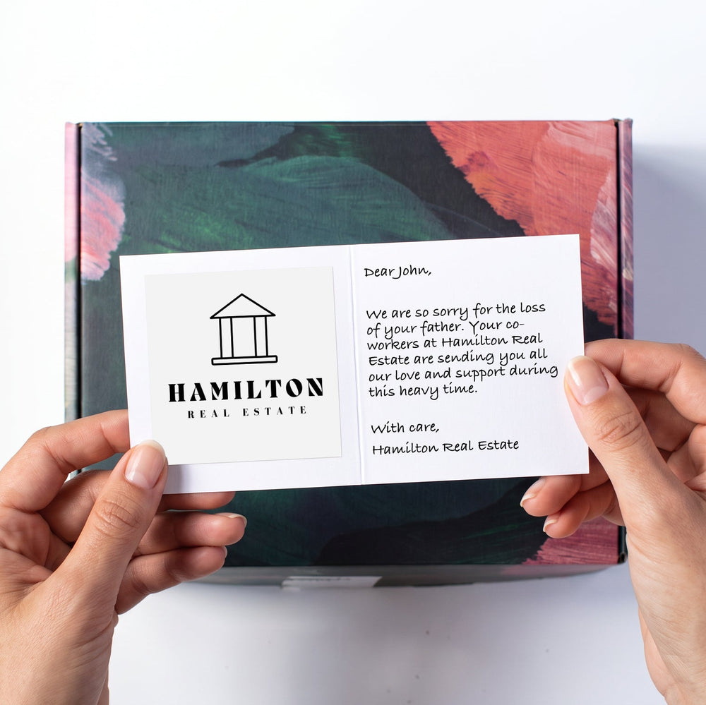 Hands holding a white card above a laurelbox.