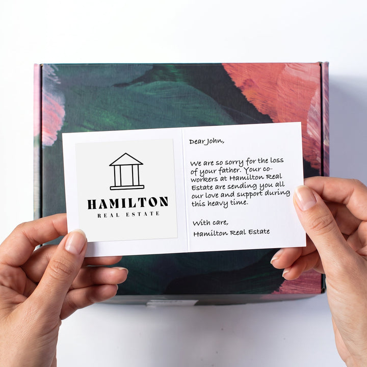 Hands holding a white card above a laurelbox.