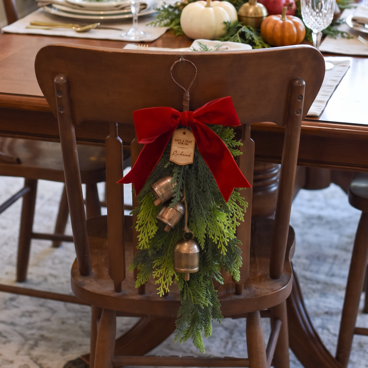 Holiday swag decor with wooden tag that says "Richard" displayed on an antique wooden chair.