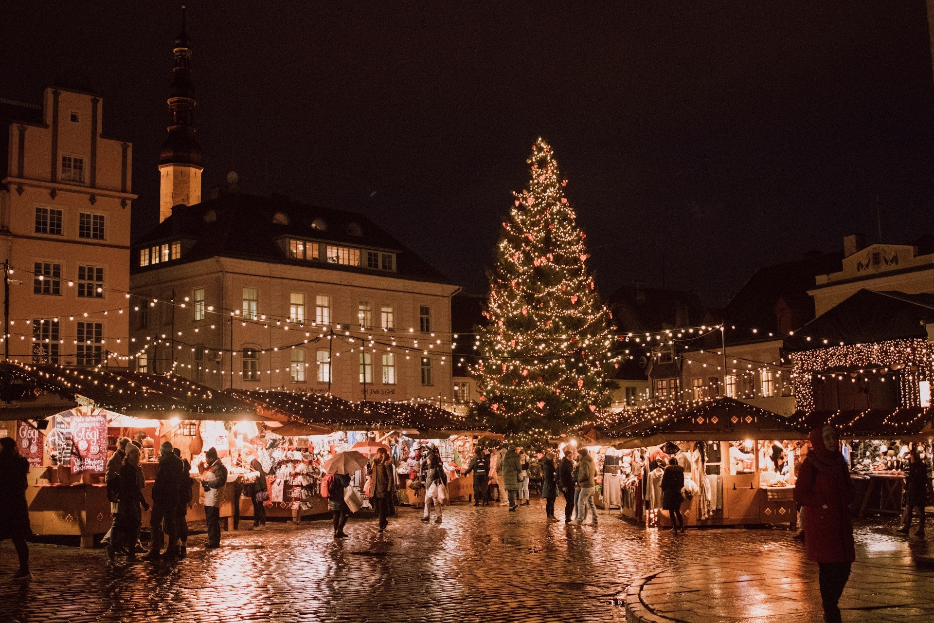 Christmas market with a large decorated tree at night.