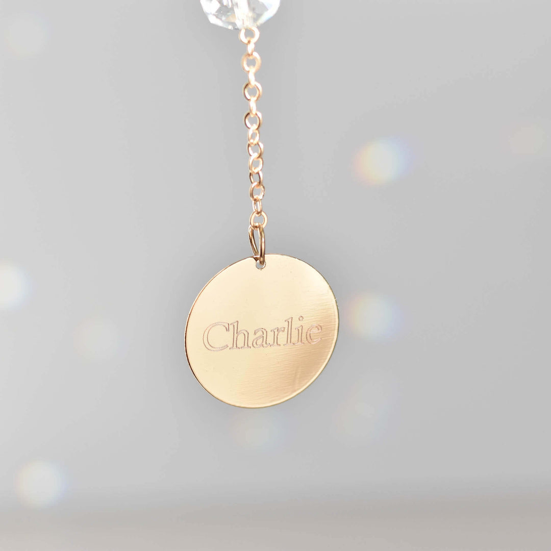 Angel Wing Sun Catcher &amp; Rainbow Maker gold circular tag with engraved name "Charlie" hanging from a chain.