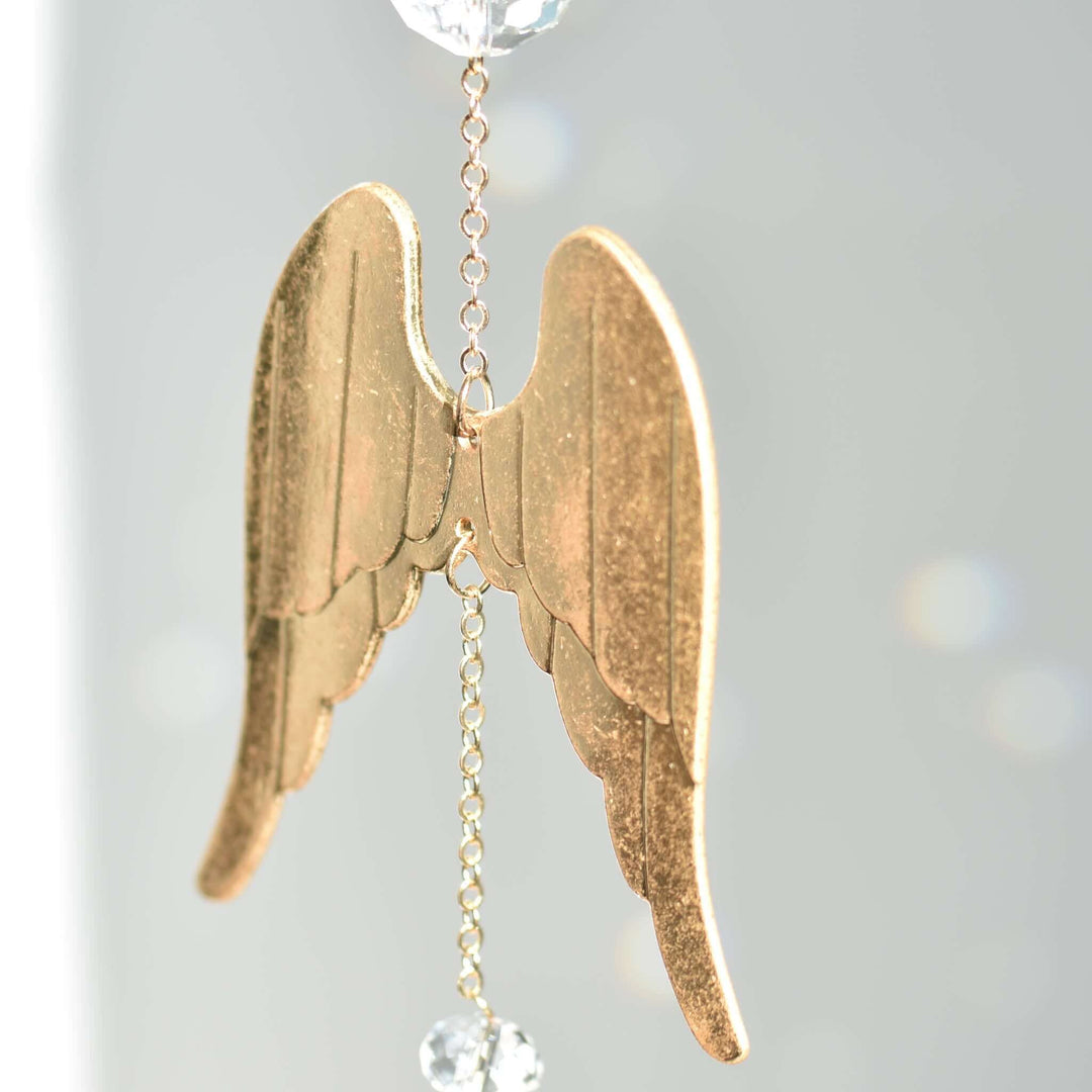 Angel Wing Sun Catcher &amp; Rainbow Maker features gold angel wings with a crystal bead, reflecting light against a gray background.