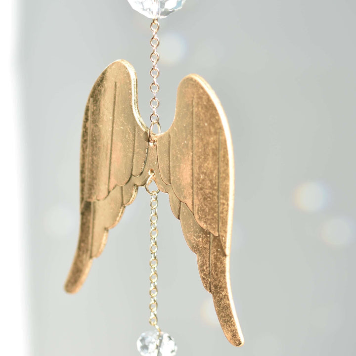 Angel Wing Sun Catcher &amp; Rainbow Maker features gold angel wings with a crystal bead, reflecting light against a gray background.