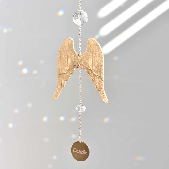 Angel Wing Sun Catcher &amp; Rainbow Maker, gold angel wings, crystal beads, engraved with "Charlie," reflecting light.