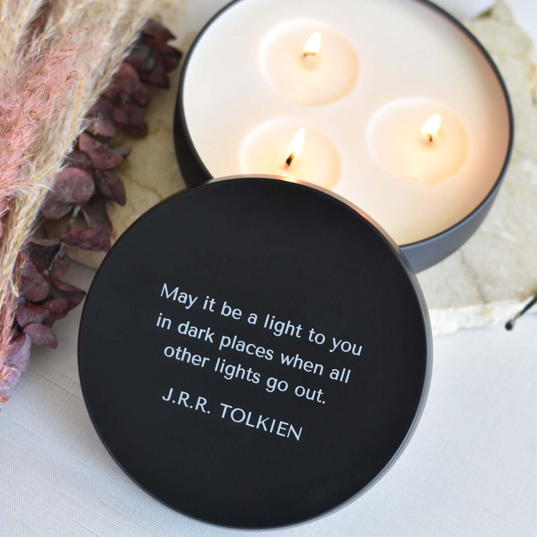 Light in Dark Places Gift Box featuring a round black candle cover with quote by J.R.R. Tolkien and lit white candles.