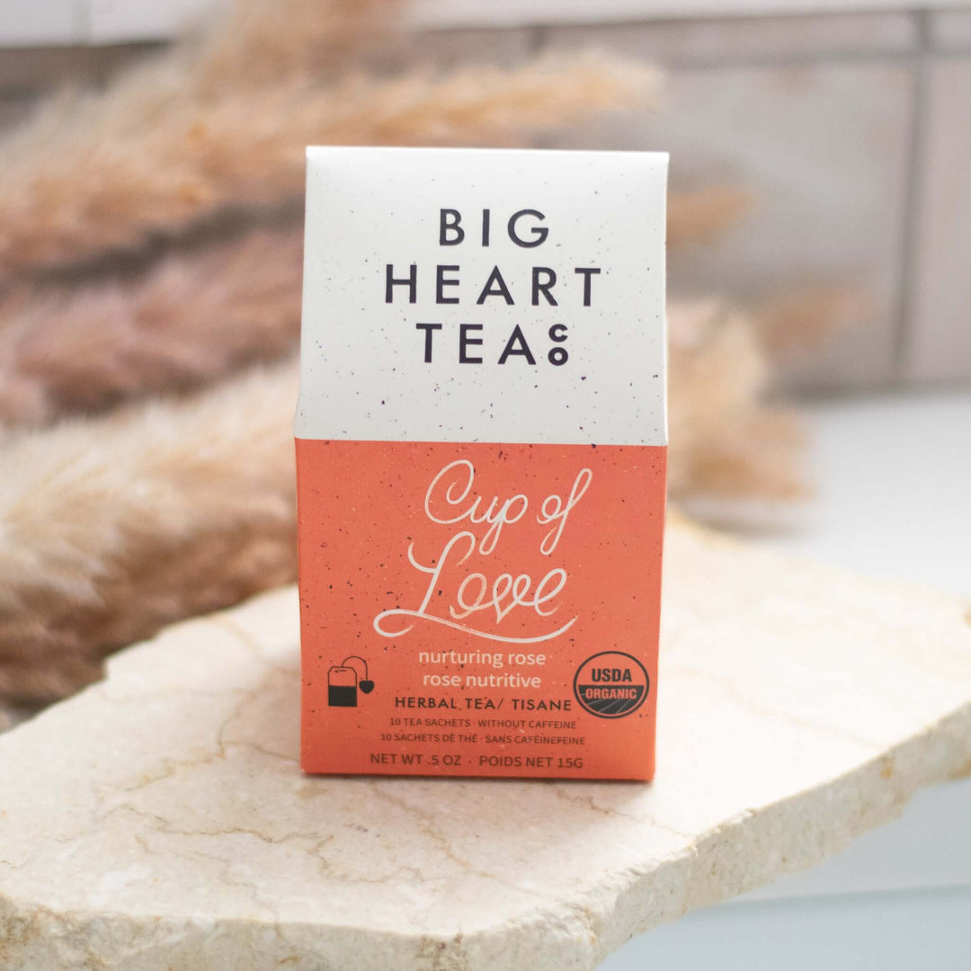 Cup of Love Herbal Tea packaging in a square box, orange base, white speckled top, with text and USDA organic logo.